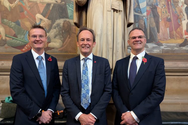Photo shows three men stood in suits and ties in the House of Lords. L-R James Davies, Martin Sawer, Malcolm Harrison
